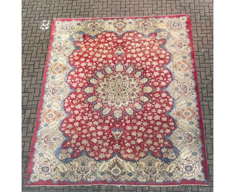 A very large Persian style Kashan carpet having a central geometric flowerhead medallion surrounded by a repeating foliate fi