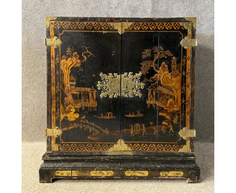 An 18th century Georgian black and gilt Japanned cabinet on stand having a rectangular top over a pair of cabinet doors inlai