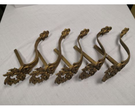 A set of four gilt metal Rococo wall brackets each having a foliate plume cresting over a shaped stem with a scalloped shell 