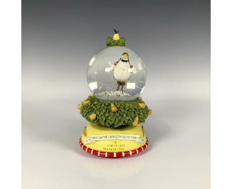 A festive Christmas snow globe adorned with a pear and green bow featuring a partridge standing atop a tree decorated with pe