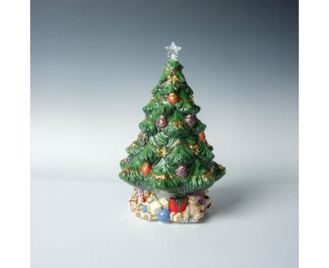 A figurine of a Christmas tree decorated with ornaments, golden-colored bows and a clear star topper. Toys and gift boxes wra