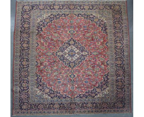 A Kashan carpet woven in colours with oval medallion, spandrels and filler motifs on a pale red ground, 390cm x 300cm Good ov