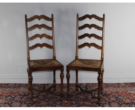 A pair of 20th century oak ladder back chairs, one with paper label 'Venduto'. 109cm high. Wear to rush seats.