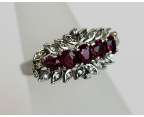 A 14K WHITE GOLD, DIAMOND AND RUBY SET RING, the face set with five graduated rubies (the largest approx 0.25ct), surrounded 