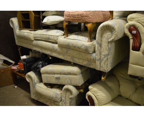 A BLUE FLORAL UPHOLSTERED THREE PIECE LOUNGE SUITE, on wooden feet with brass caps and casters, comprising of a three seater 