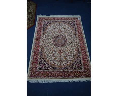 A KESHAN STYLE RUG, red, blue and cream ground, multi strap border, foliate design and central medallion, approximate size 16