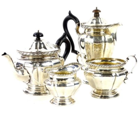 A George V silver four piece tea set, the teapot and hot water jug with ebonised knop and handle, decorated overall with face