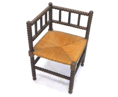 A stained beech bobbin turned corner chair, with a rush seat.