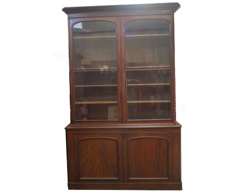 A Victorian mahogany cabinet bookcase, with moulded overhang cornice over two arch moulded and glazed doors, revealing adjust