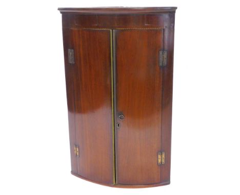 An early 19thC mahogany and chequer banded bow fronted corner cabinet, with two plain doors, 103cm H, 66cm W.