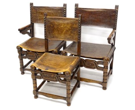 A pair of late 19th/early 20thC oak armchairs, each with a brown leather back and seat, on bobbin turned supports, with carve