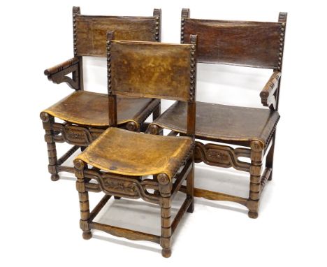 A pair of late 19th/early 20thC oak armchairs, each with a brown leather back and seat, on bobbin turned supports, with carve