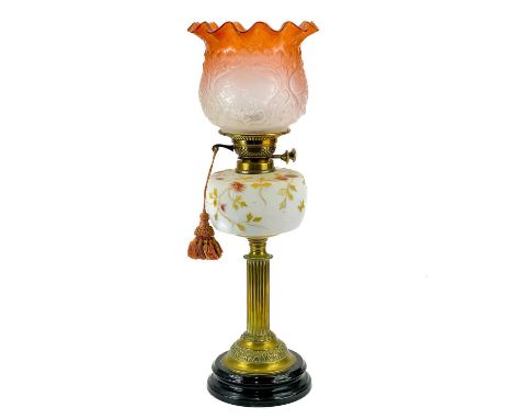 A Victorian brass oil lamp with opaque glass reservoir decorated with enamels. Orange glass shade, height 59cm.Small losses t