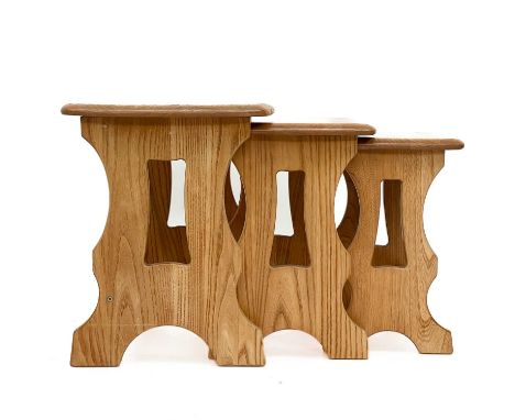 A nest of three Ercol light elm occasional tables. With pierced trestle end supports, the largest height 42cm, width 57cm, de