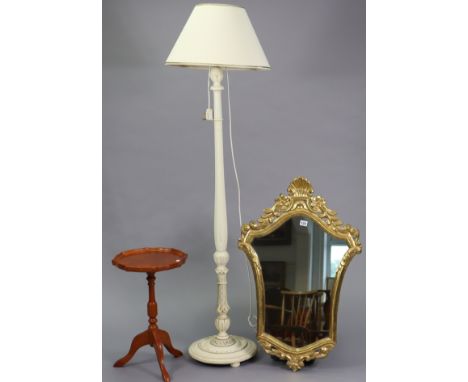 A gilt-frame shield-shaped wall mirror, 22” x 34”; together with a white painted &amp; carved wooden standard lamp with shade