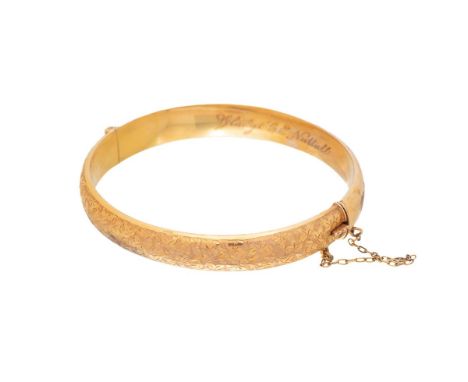 A Victorian 9ct gold bangle of hinged form with one half engraved with ivy leaves, dedication engraved inside, internal diame