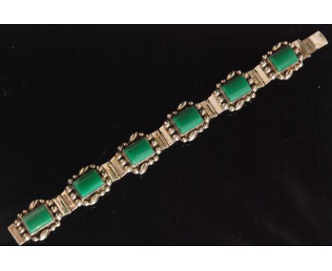 A Mexican Sterling silver panel link bracelet composed of six hinged shaped rectangular panels each inset with a green stone,