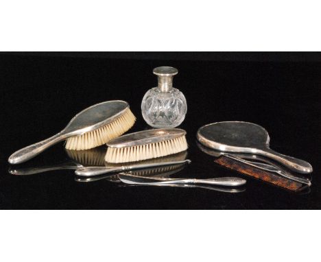 A George V hallmarked silver seven piece dressing table set comprising of a silver mounted cut glass globular scent bottle, t