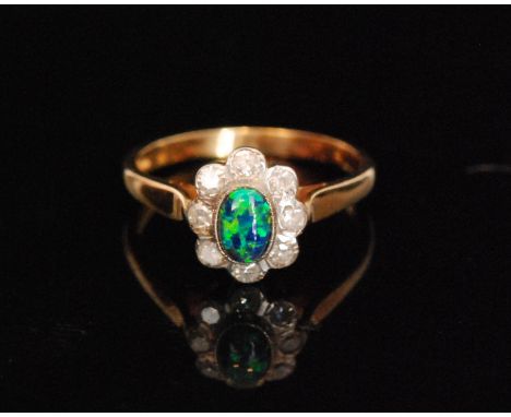 A 9ct hallmarked synthetic black opal and diamond cluster ring, oval central opal within a eight stone diamond surround, ring