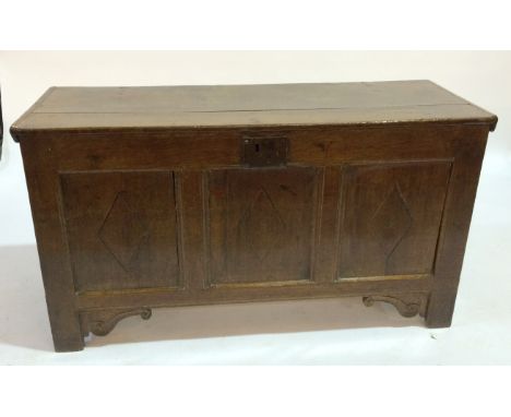 An oak coffer with triple fielded panel front, the frieze inlaid with spurious date of 1582, retains candle box and raised to