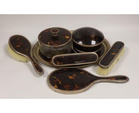 A matched George V silver and tortoiseshell mounted seven piece dressing table set, including a trinket box.