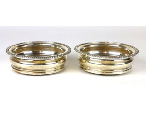 A pair of silver plated wine bottle coasters with wooden bases and central crested silver plated button.  d. 15.5 cm (2)