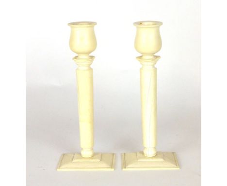 A pair of ivory candlesticks, tulip form sconce on a tapering cylindrical column. h. 19 cm. (2) CONDITION REPORT: Good, bar a