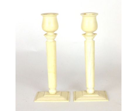 A pair of ivory candlesticks, tulip form sconce on a tapering cylindrical column. h. 19 cm. (2) CONDITION REPORT: Good, bar a