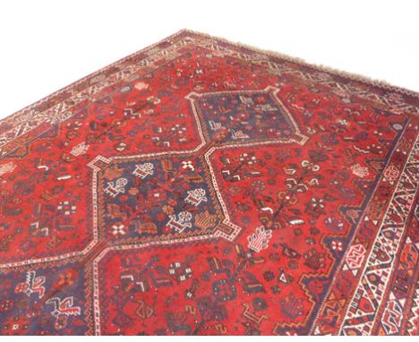 An Iranian carpet, triple lozenge medallion on a red ground with stylized flowers and birds inside a triple border. 295 cm x 