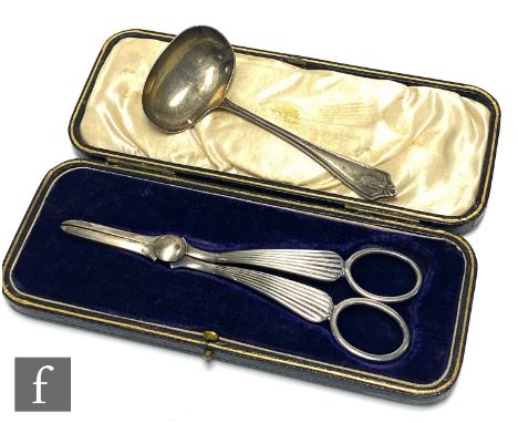 A cased pair of hallmarked silver grape scissors with reeded stems, with a small sauce ladle, Sheffield 1913 and Birmingham 1