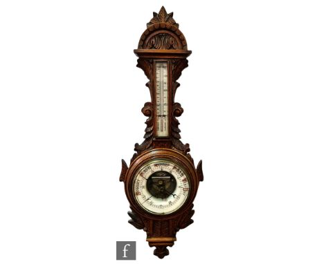 A Victorian carved oak aneroid barometer, the circular dial below a thermometer, leaf carved and arch border, height 95cm. 