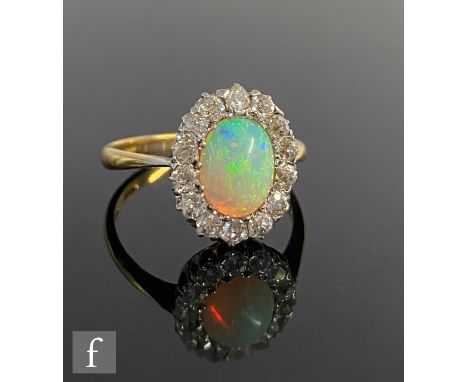 An early 20th Century opal and diamond cluster ring, central oval opal length 10mm, within a fourteen stone old cut diamond s