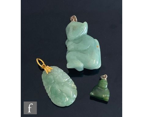 An oval carved jade pendant with gold pendant loop, with a similar carved study of a monkey and a small Buddha. (3) 