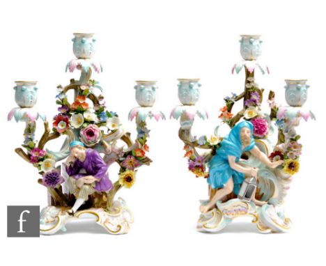 A pair of late 19th Century Meissen three branch candelabra, the first modelled as Diogenes holding a lantern and sat on an e