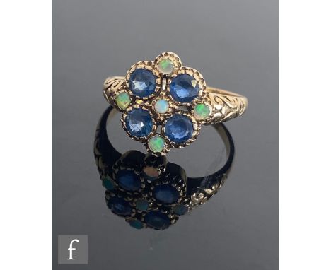 A 9ct sapphire and opal cluster ring, central opal within a four stone sapphire surround spaced by further opals to scroll de