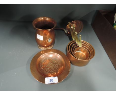 A selection of vintage copper wares including graduated measures and Celtic style dish