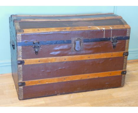 An early 20th century dome topped twin handled trunk, with gilt brass mounts, the hinged lid opening to reveal fabric lined i
