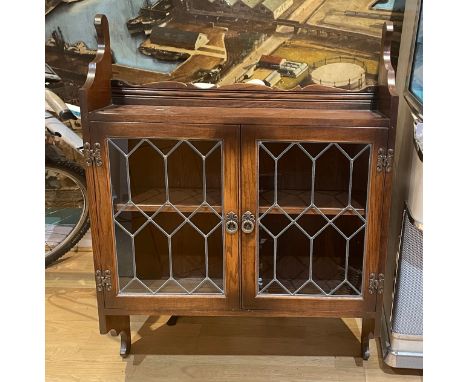 An oak wall mounted display cabinet, the twin glazed doors having leaded lights opening to reveal a fitted shelf, 87x114cm. 