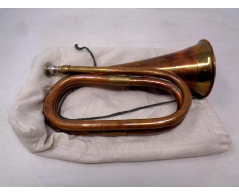 An antique copper and brass bugle in a bag 