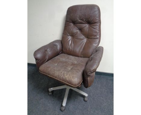 A 20th century teak framed brown button leather upholstered swivel armchair 