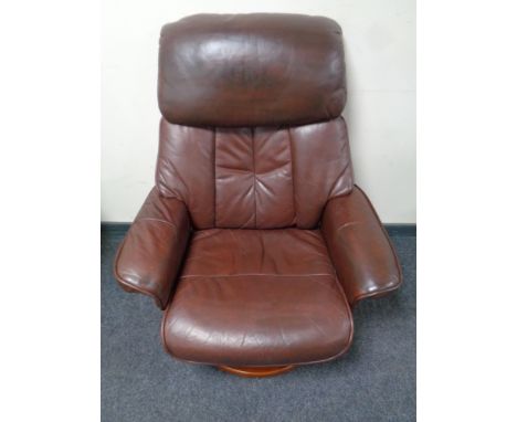 A wood framed brown leather manual reclining swivel armchair and similar footstool 