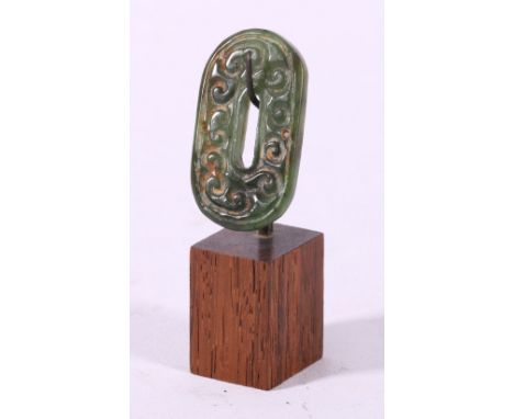 Carved jade bi or oval pierced disc decorated with band of scrolling waves, on stand, jade 5cm long