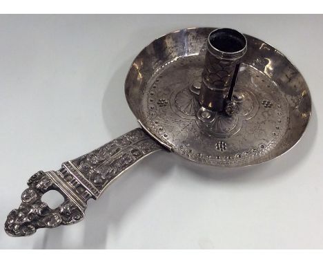 An unusual circular silver chamber stick attractively decorated with flowers and figures. Punched to side. Approx. 150 grams.