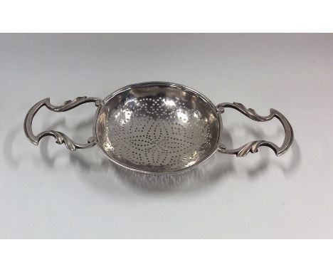 A Georgian silver lemon strainer with double cast handle. London. By PG. Approx. 58 grams. Est. £150 - £200.