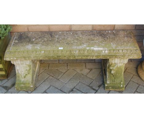 A reconstituted 'Haddonstone' garden two seater bench raised on leaf capped end supports