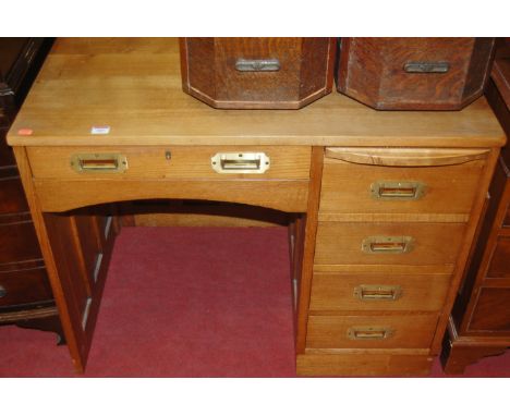 A light oak single pedestal desk in the campaign style, having flush brass handles