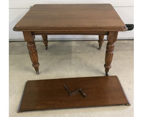 A vintage oak winding draw leaf dining table with turned legs on ceramic castors. Complete with extra leaf and winding handle
