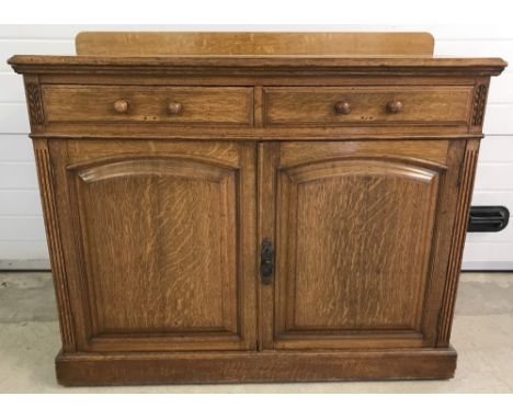 A vintage light oak Maple & Co double sideboard with carved and fluted design to sides. 2 drawers over a double door cupboard