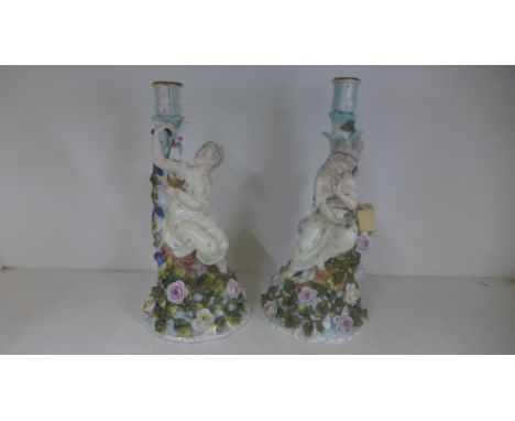 A pair of Continental porcelain figural candlesticks both with figures of ladies with birds surrounded by floral and foliate 