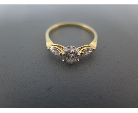 A three stone diamond ring set in yellow gold, the central diamond approx 1/2ct, diamond flanked by two smaller oval cut ston